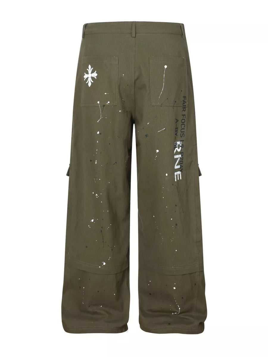 Olive cotton cargo pants with white paint splatter design and graphic text detail.