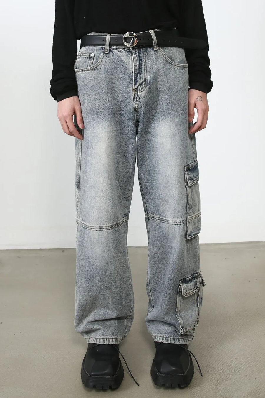 Baggy distressed medium wash denim cargo pants with multiple pockets.