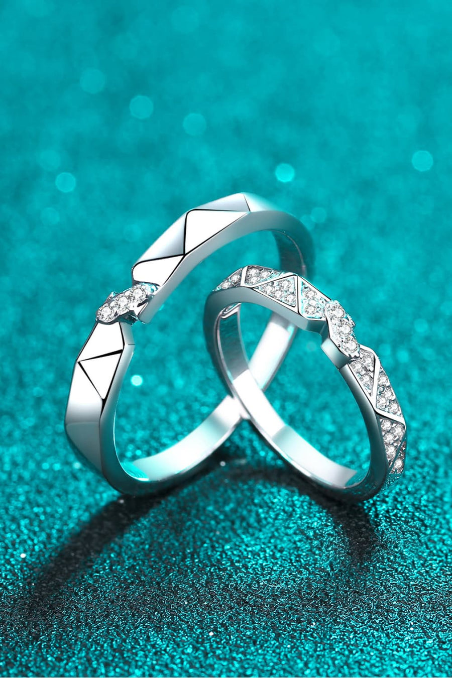 Geometric rhodium pavé ring set with cubic zirconia accents on a teal sparkly background.