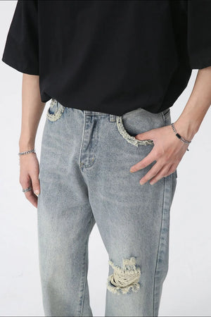 Distressed wide-leg denim jeans in medium wash with raw edge pockets and knee rip.