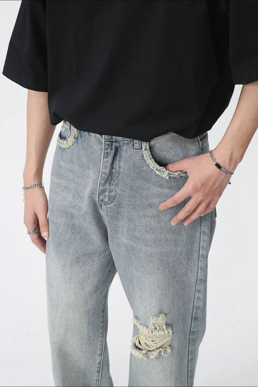 Distressed wide-leg denim jeans in medium wash with raw edge pockets and knee rip.