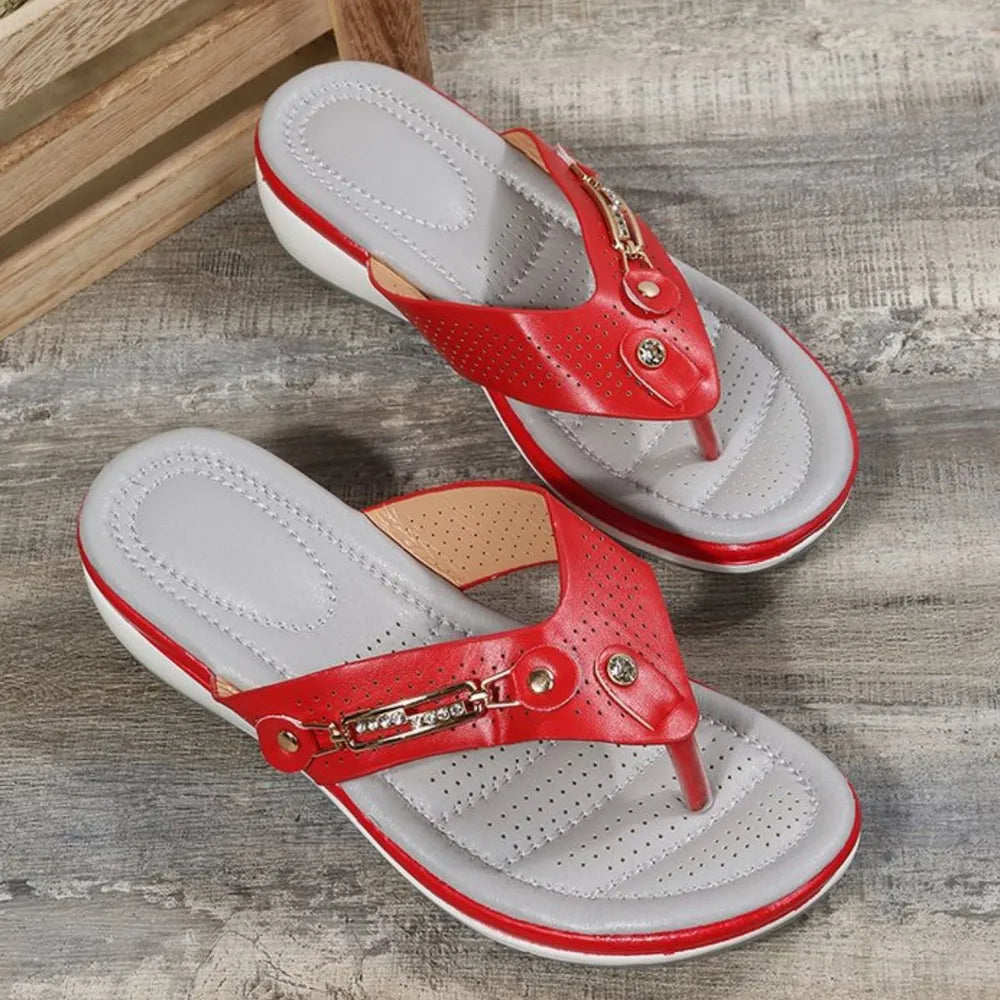 Red perforated thong wedge sandals with embellishments and a grey footbed.