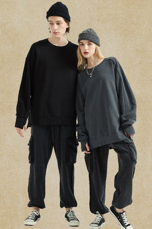 Oversized sweatshirt in dark gray with raw-edge seams and crew neck, styled casually.