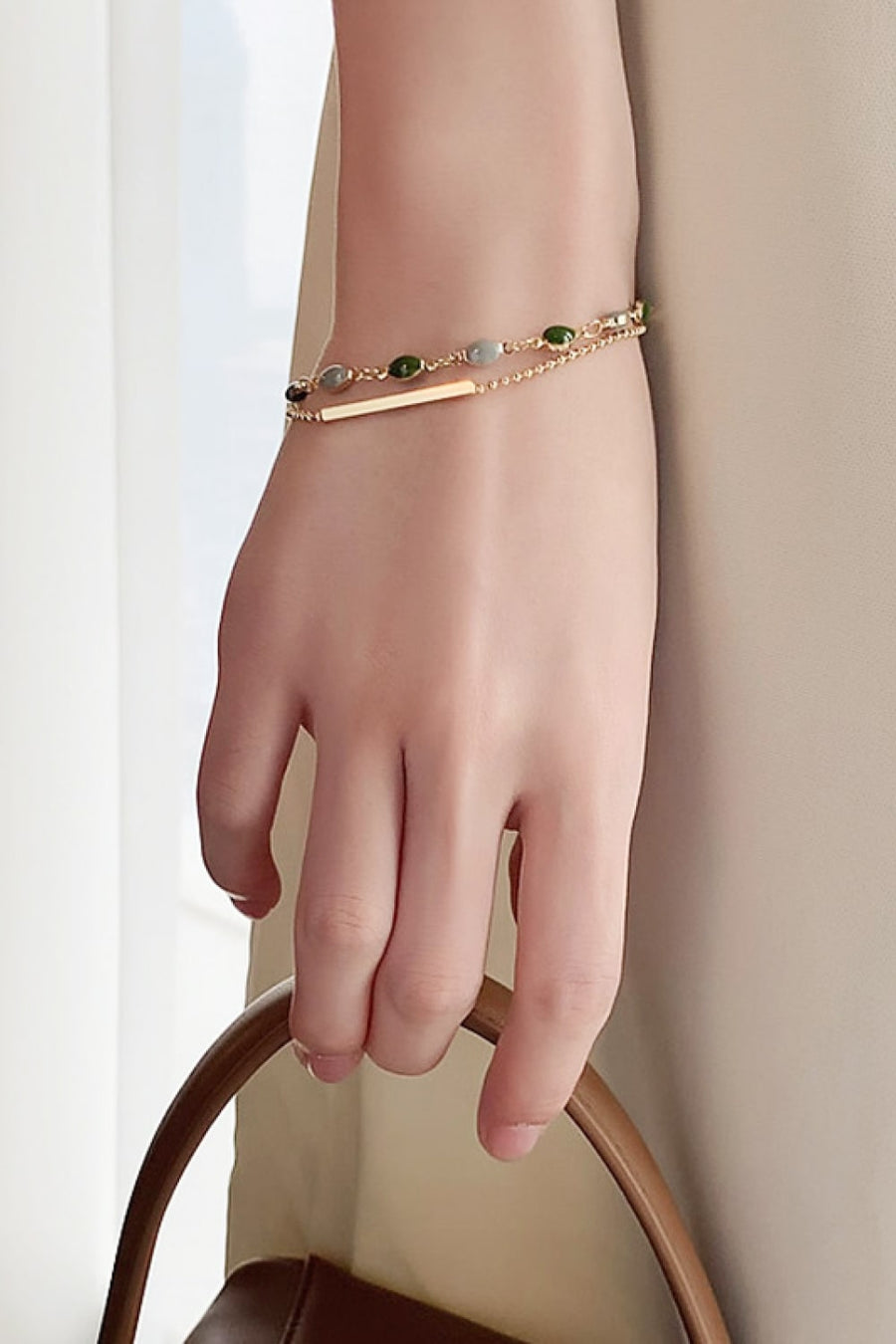 Dual chain bracelet in gold with green stones and a bar accent