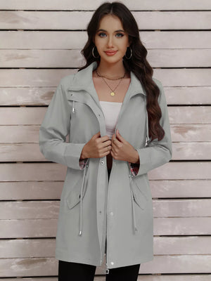 Light gray drawstring trench coat with snap-down details and a zippered front.