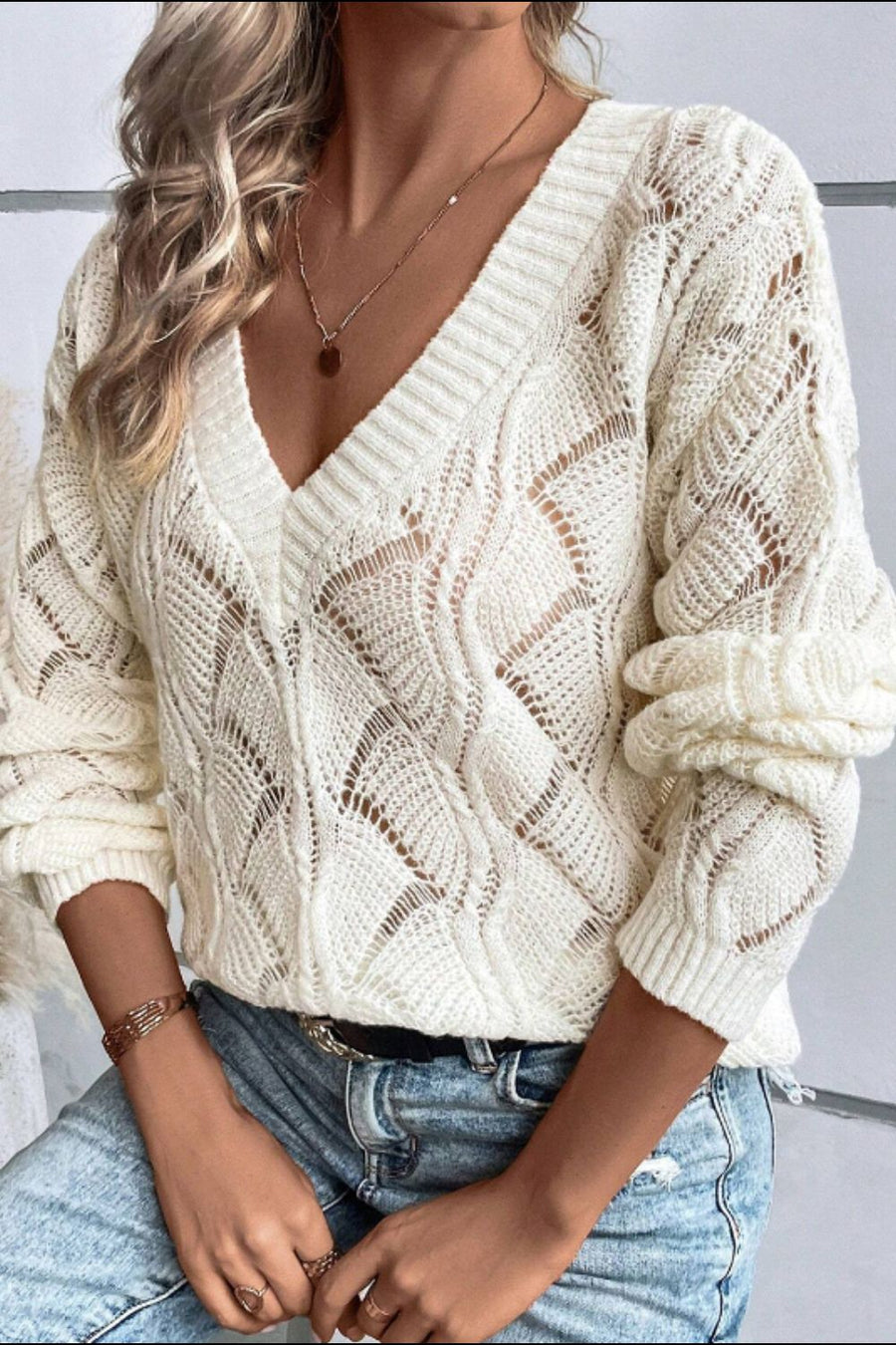 Ivory openwork knit V-neck pullover sweater with diamond pattern and ribbed cuffs.