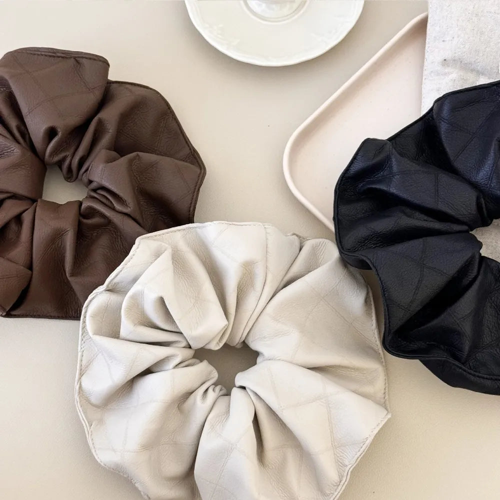 Quilted faux leather scrunchies in beige, brown, and black with a diamond pattern.