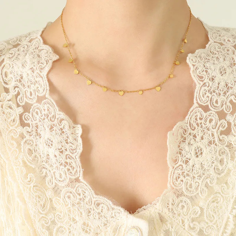 Gold heart charm chain necklace with delicate dangling hearts.