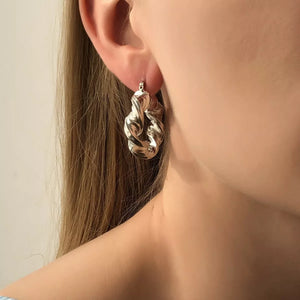 Textured hoop earrings in silver with a twisted knot design.