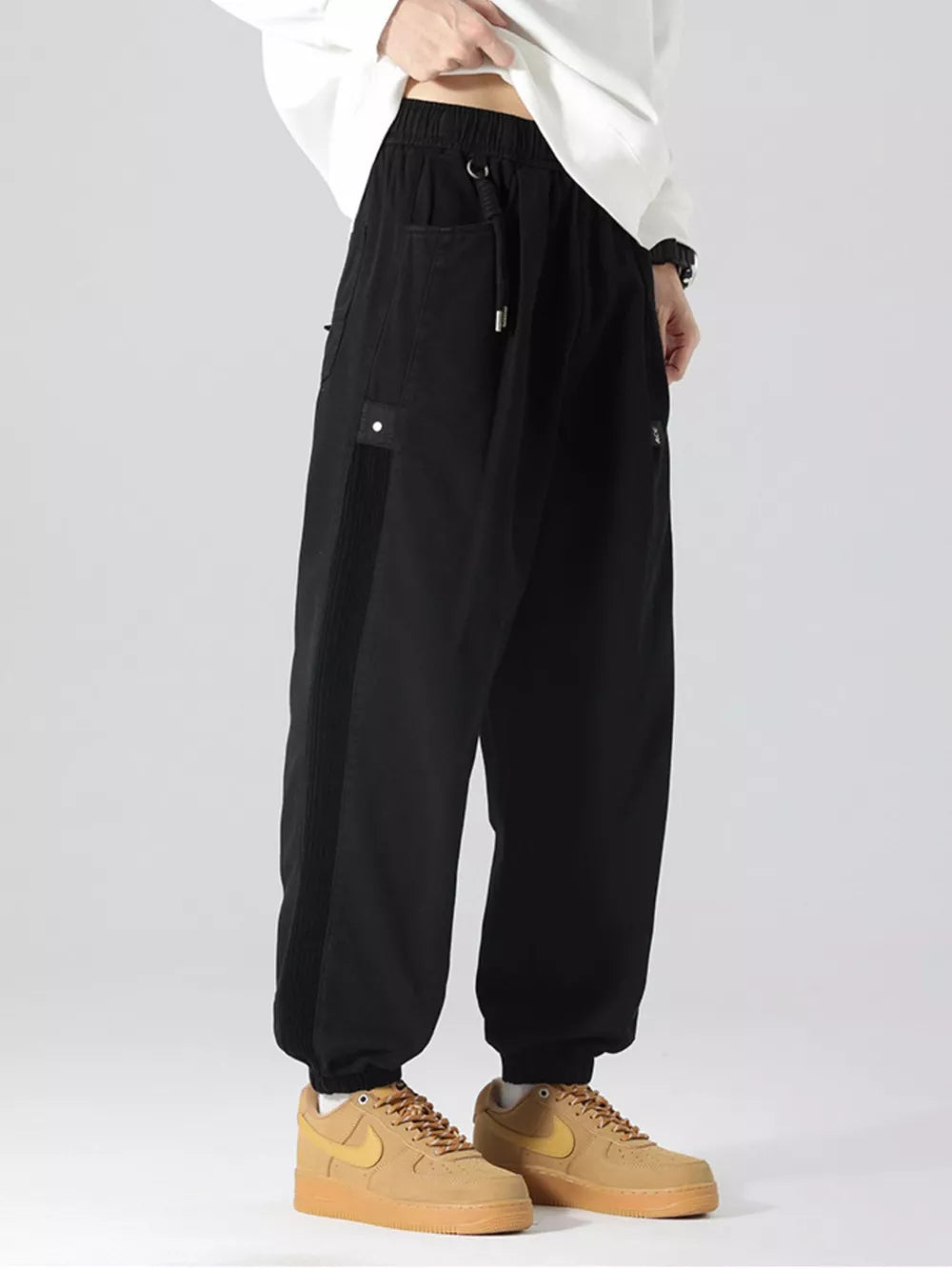 Black oversized cargo joggers with drawstring and side stripe detail.