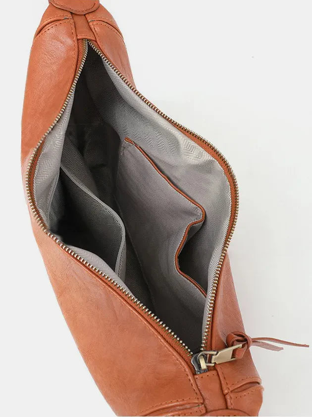 Terracotta leather crossbody bag with open interior showing pockets and chevron lining.
