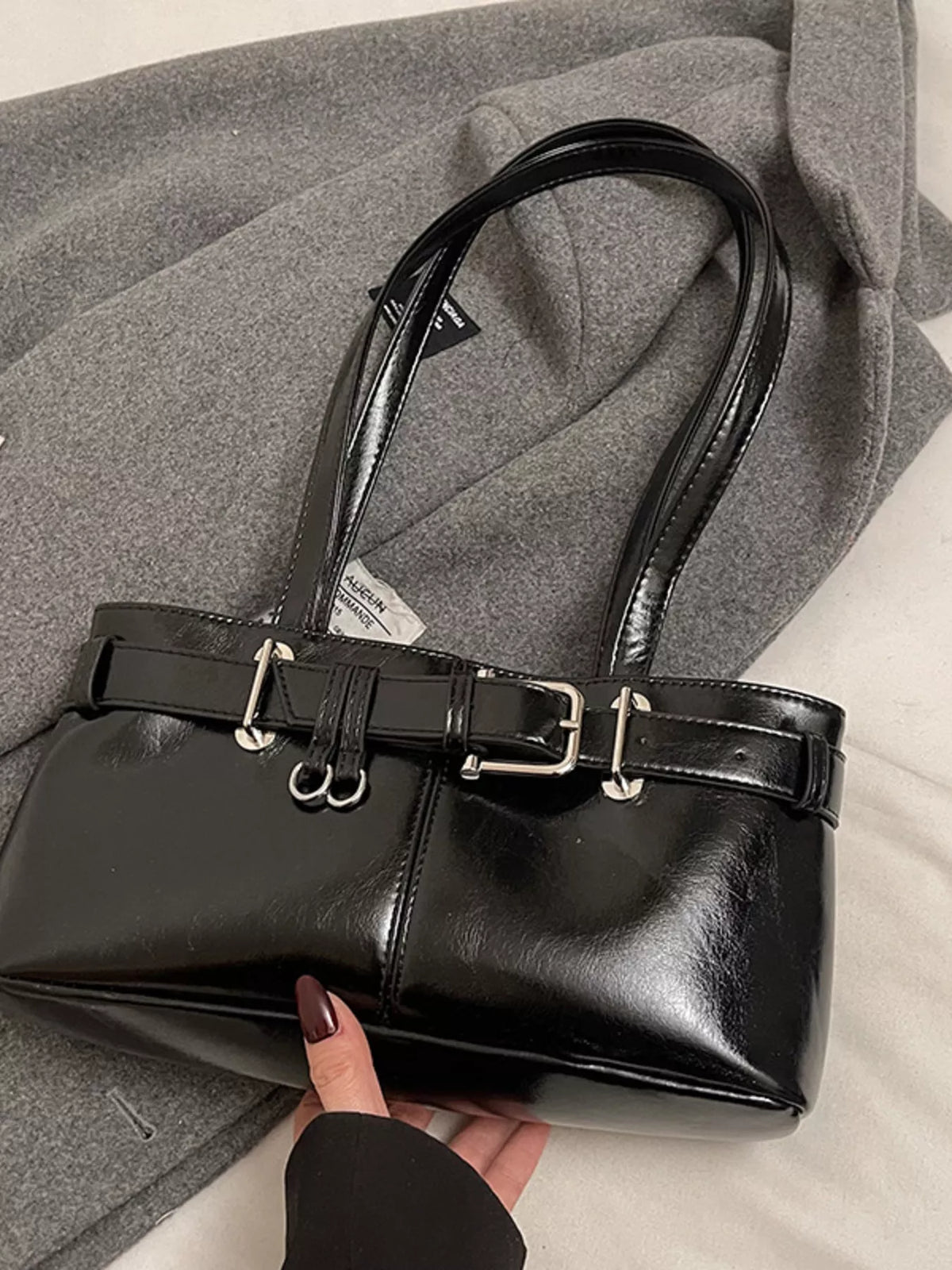 Black patent shoulder bag with buckle detail and silver hardware.