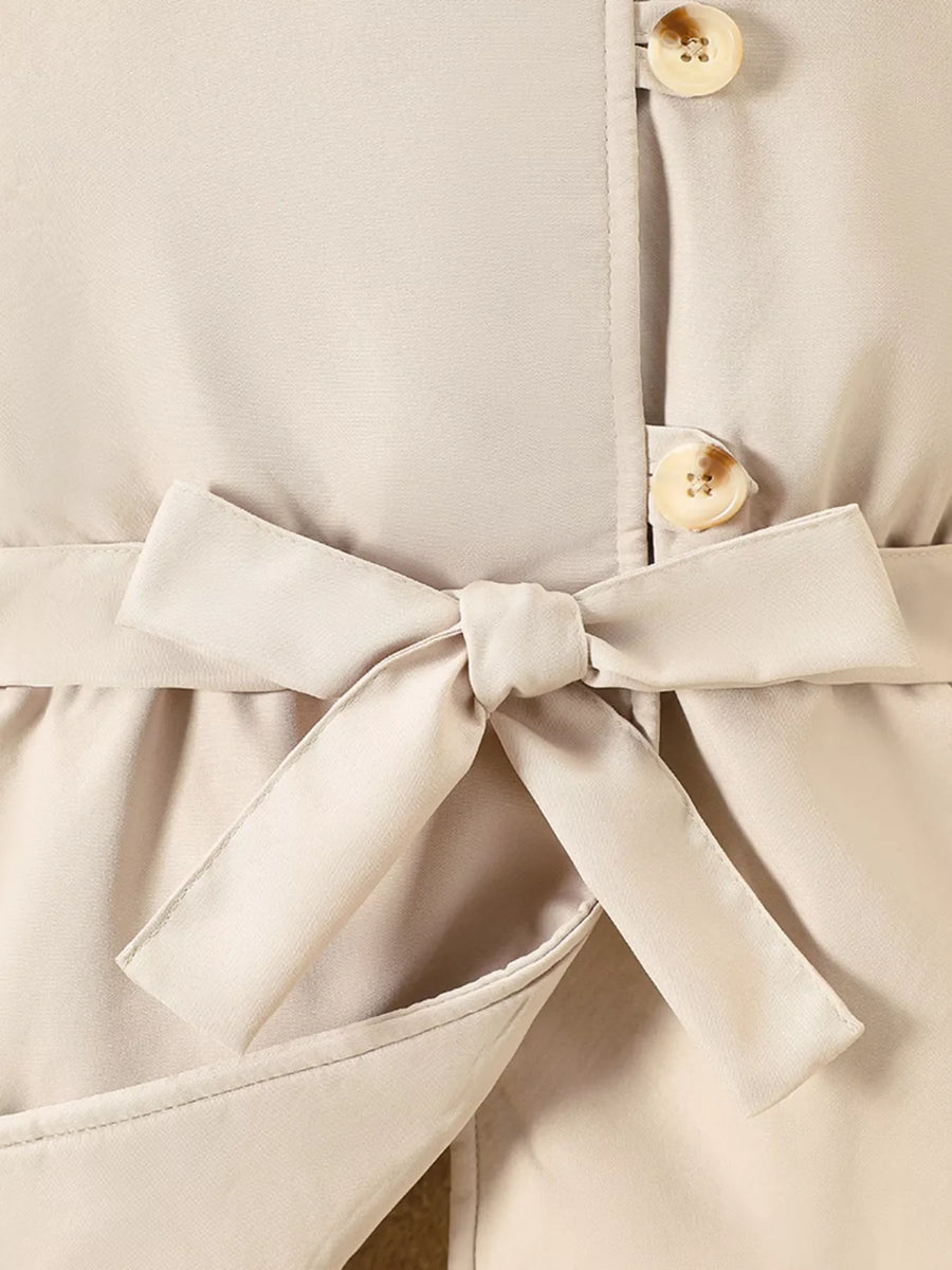 Apricot belted coat with bow detail and button closure.