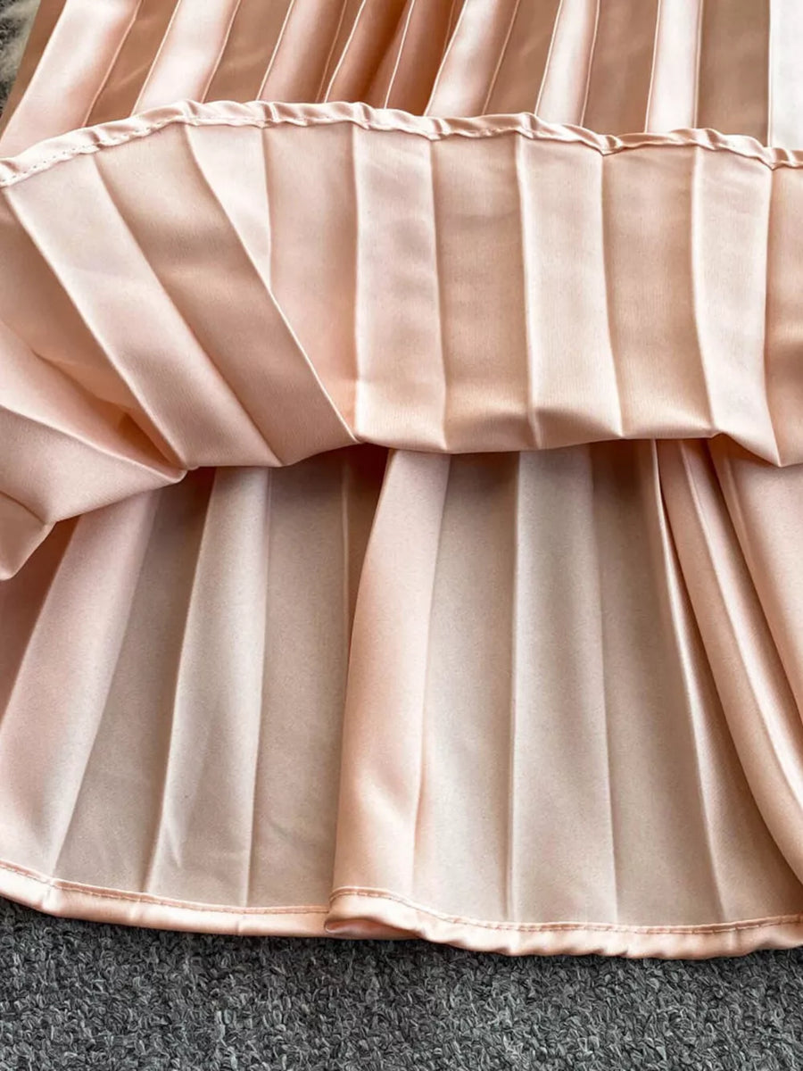 Elegant pink pleated maxi dress with satin finish and cutout detail.