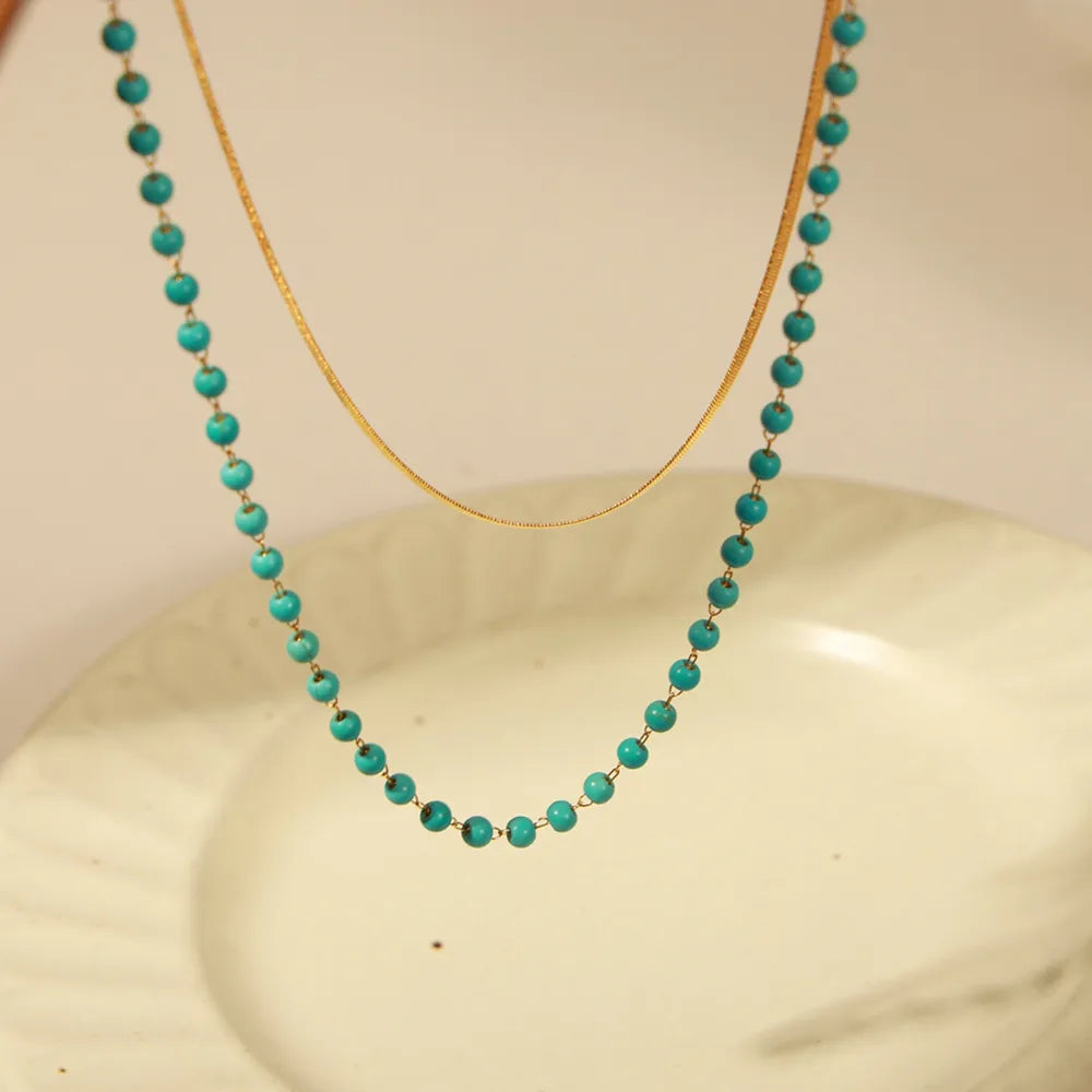 Gold layered necklace with turquoise beads and a delicate snake chain.