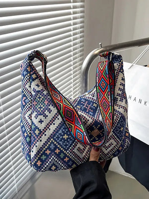 Blue embroidered hobo bag with geometric pattern and colorful strap.