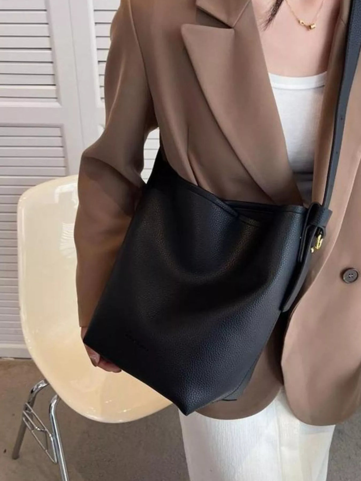Black pebbled PU leather shoulder bag with adjustable strap and gold buckle detail.