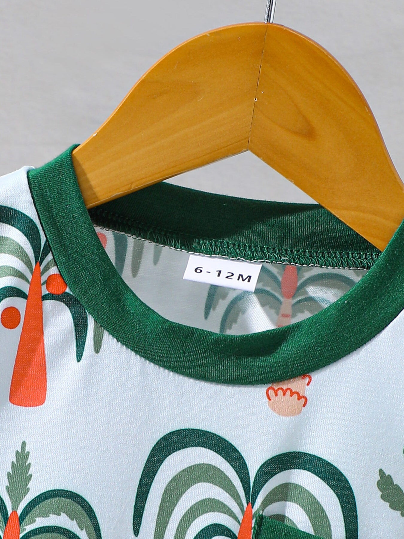Baby tee and shorts set with tropical palm print, green trim, and cotton fabric.