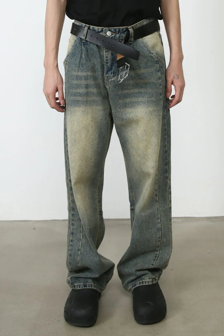 Faded wash baggy carpenter jeans in medium with a distressed look and a black belt.