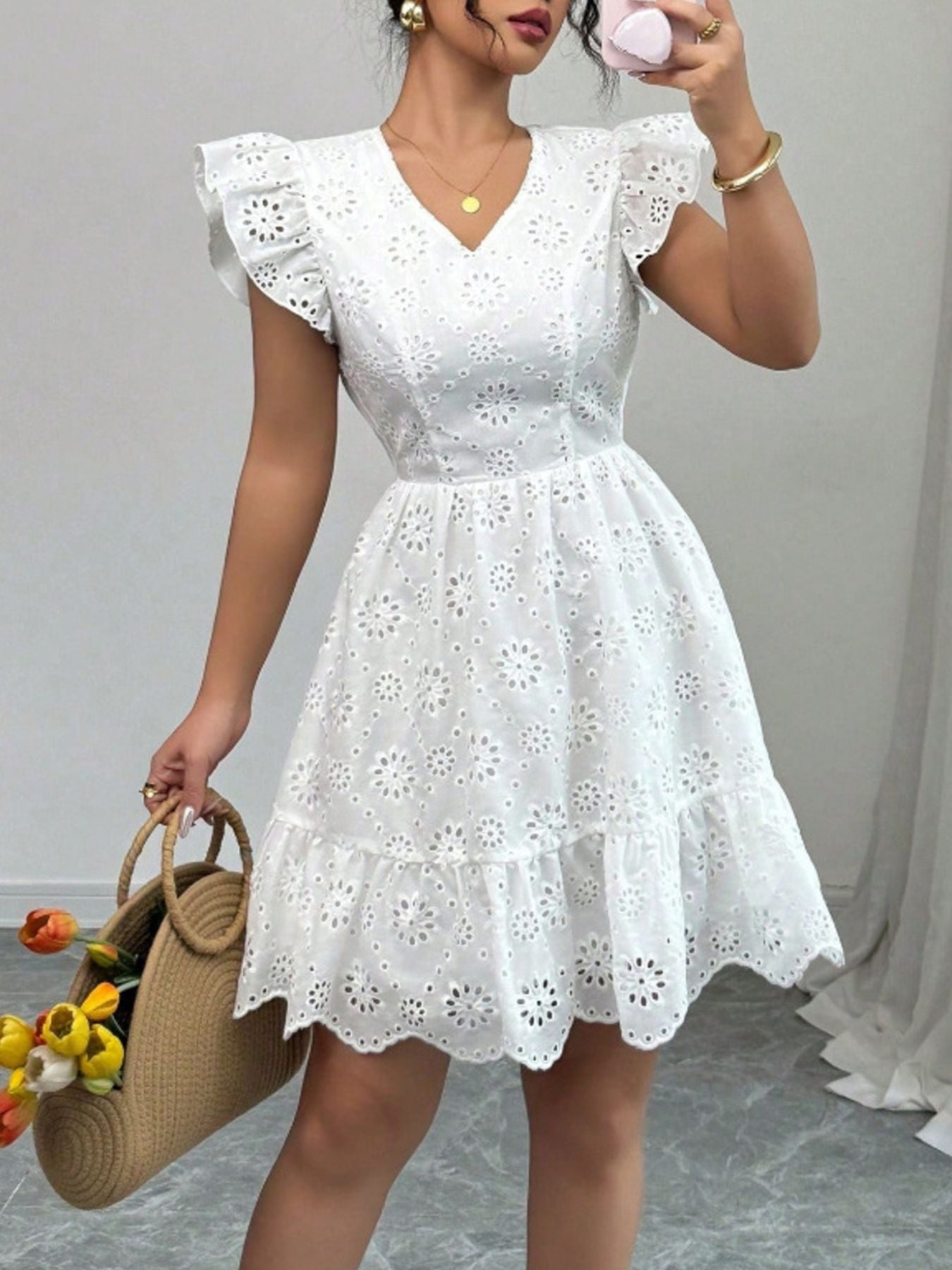 White embroidered mini dress with ruffle sleeves, V-neck, and tiered hem.