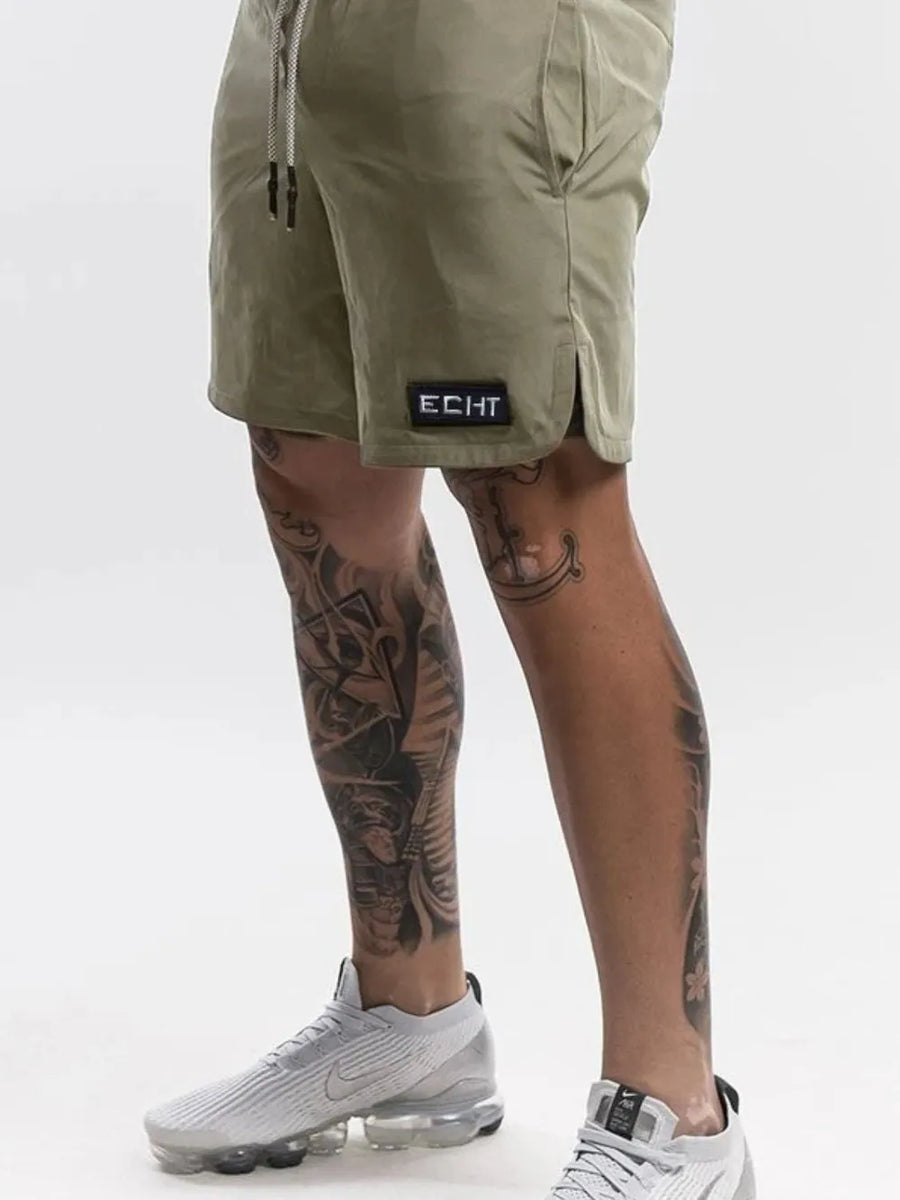 Army green performance drawstring shorts with black logo patch and side slits.