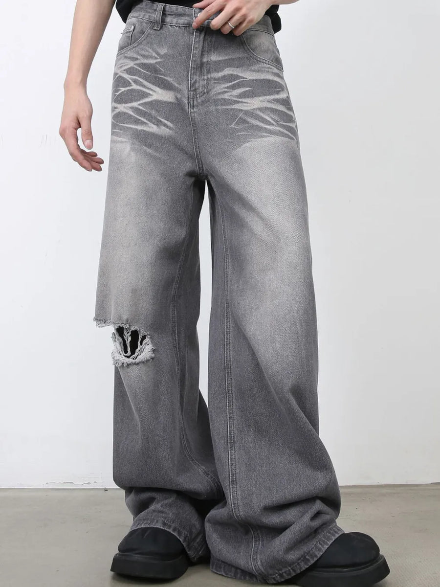 Dark gray distressed wide-leg jeans with a ripped knee detail and sculpted silhouette.