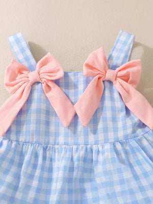 Blue gingham baby dress with pink bow shoulder straps and ruffled skirt.