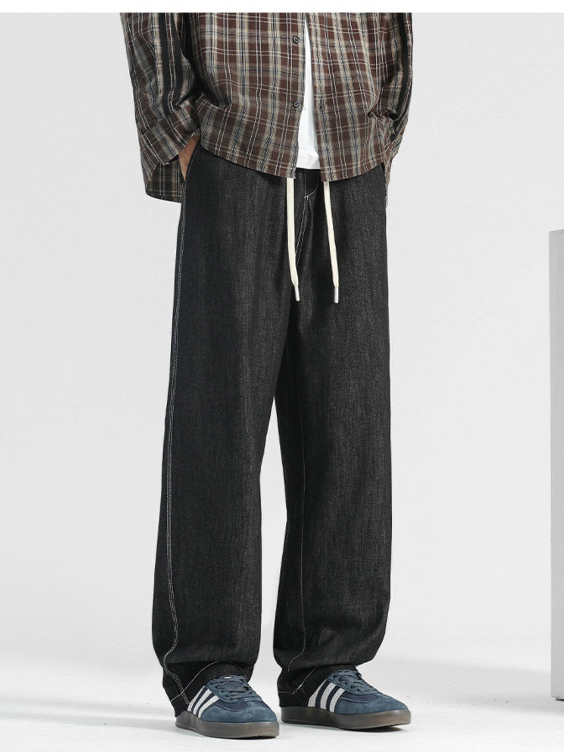 Men's black wide-leg jeans with drawstring and contrast stitching.