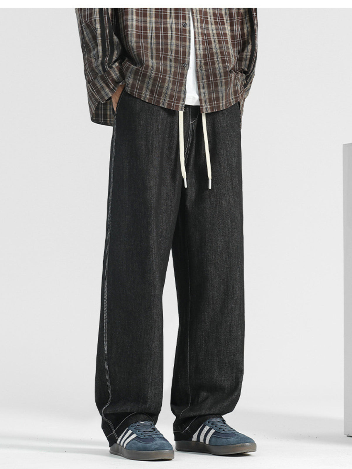 Men's black wide-leg jeans with drawstring and contrast stitching.