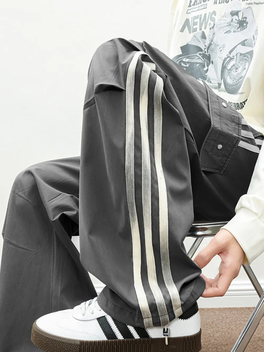 Oversized cargo pants in dark gray with white side stripes and flap pockets.