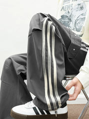 Oversized cargo pants in dark gray with white side stripes and flap pockets.