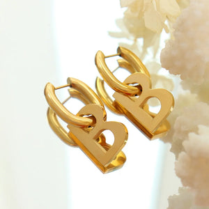 Gold titanium statement hoop earrings with bold letter charms