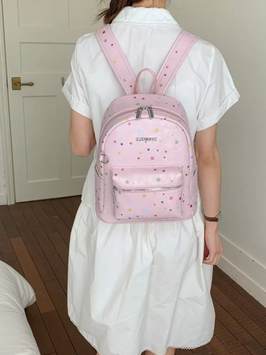 Blush pink mini backpack with colorful star embellishments and front zip pocket.