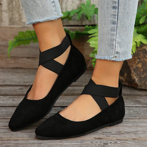 Black crisscross strap pointed-toe ballet flats with elastic ankle straps.