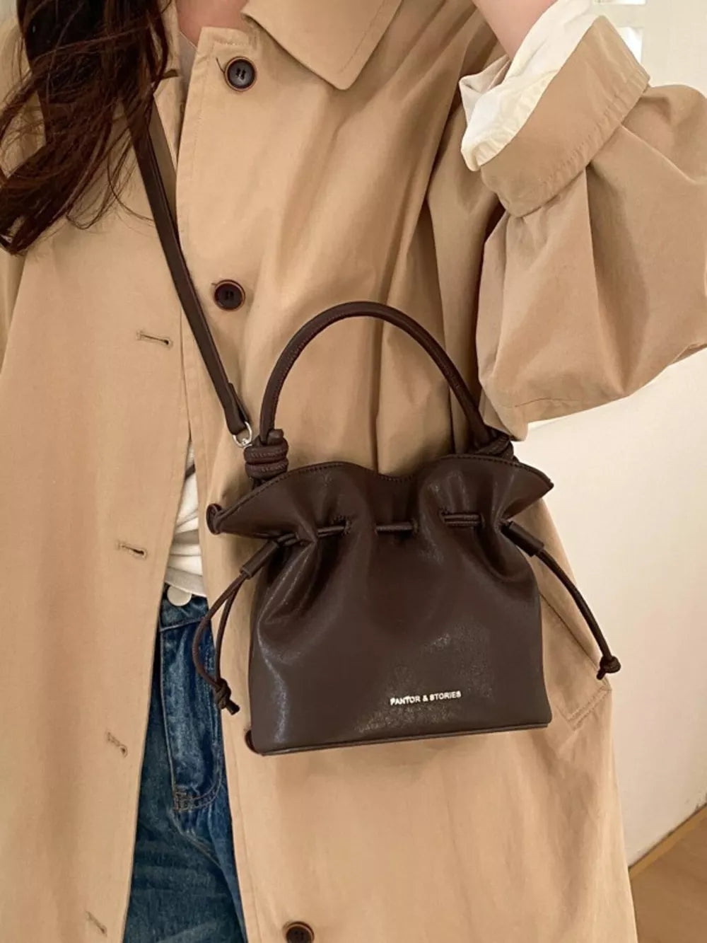 Brown pu leather cinch-top crossbody bag with drawstring closure and top handle.