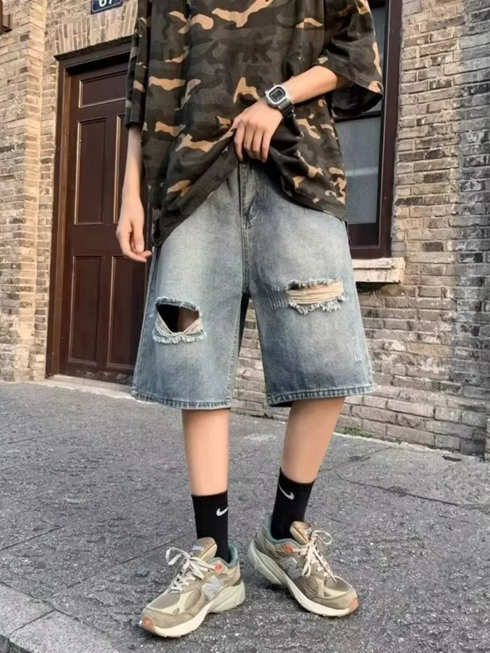 Relaxed fit distressed denim shorts in blue with rips and raw hem.