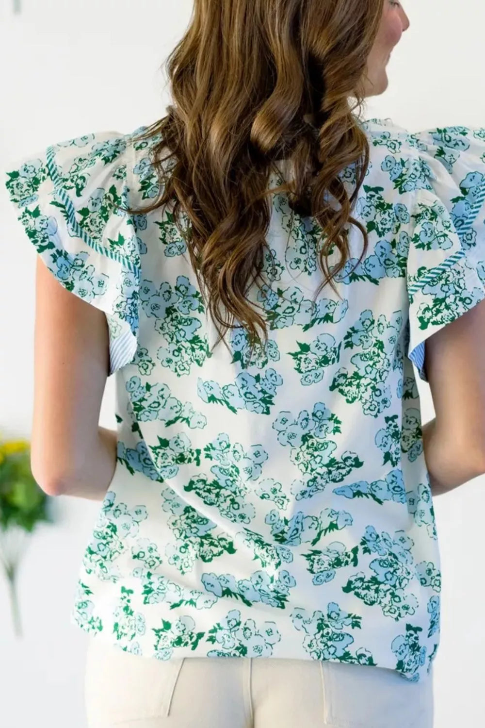 Floral print polyester blouse with flutter sleeves and ruffled details.