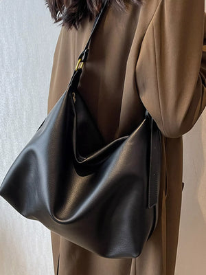 Black sculptural PU leather shoulder bag with adjustable strap and gold hardware detail.