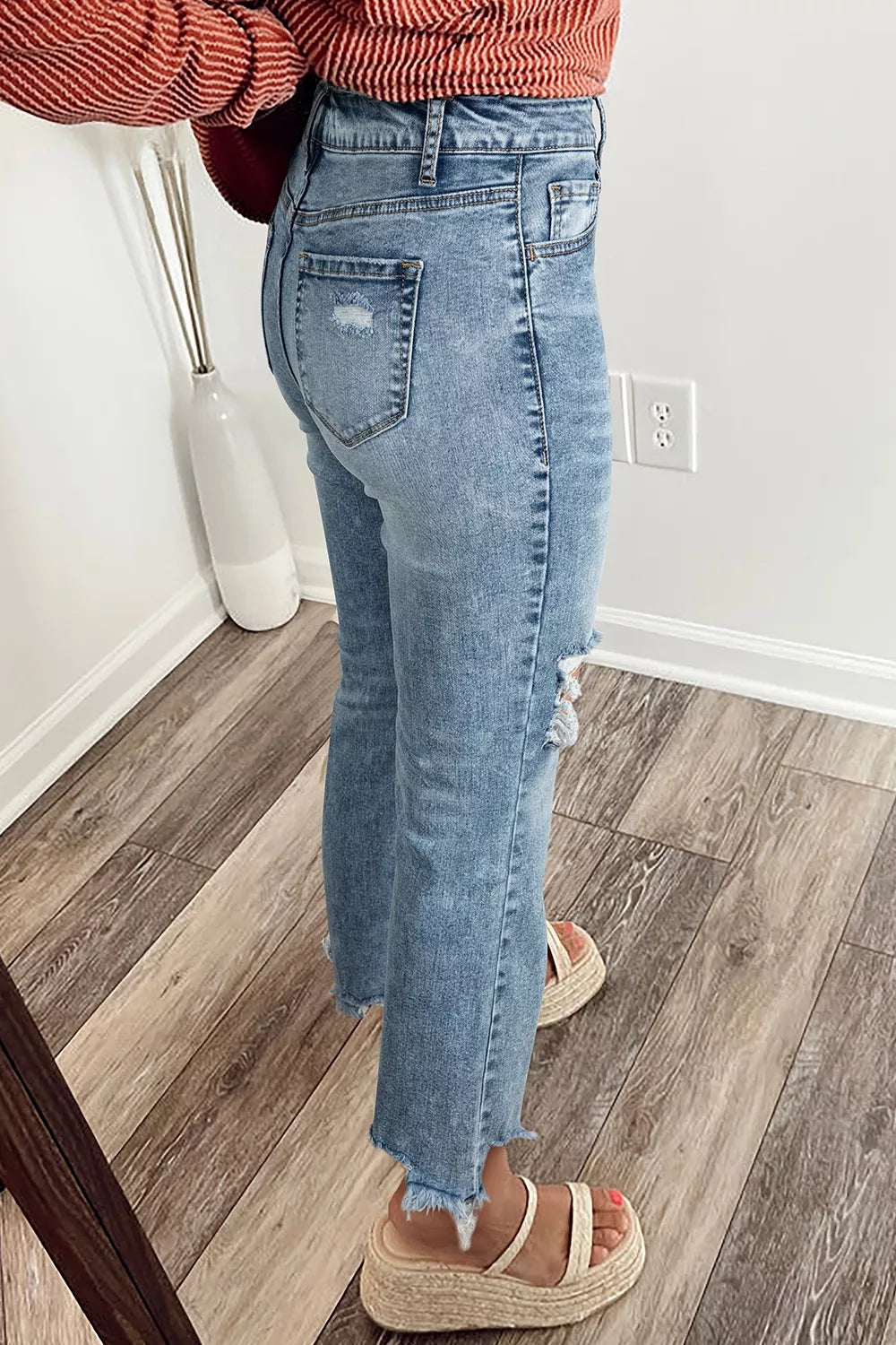 Distressed light wash denim flare jeans with open knees and frayed hem.