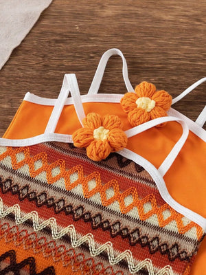 Orange baby halter dress with crochet flower details and zigzag knit pattern.