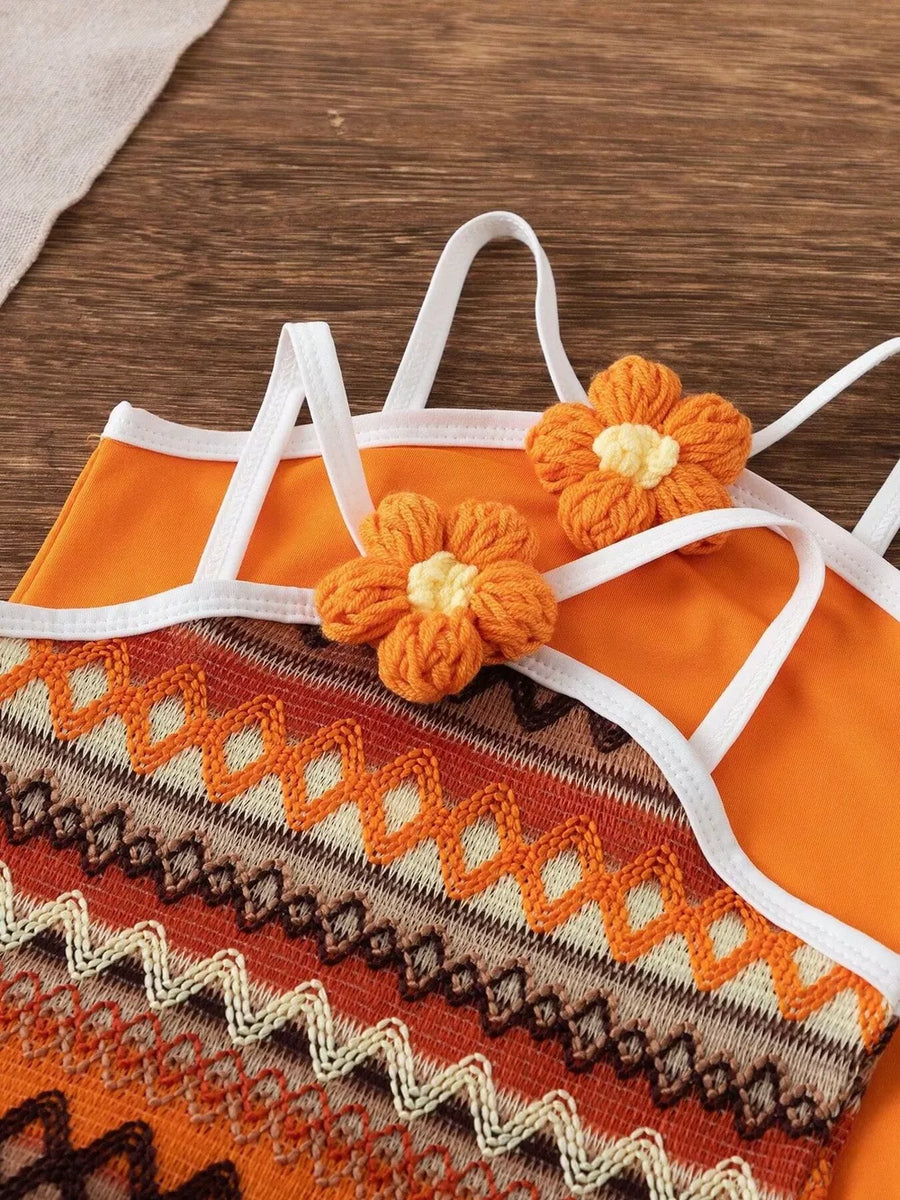 Orange baby halter dress with crochet flower details and zigzag knit pattern.