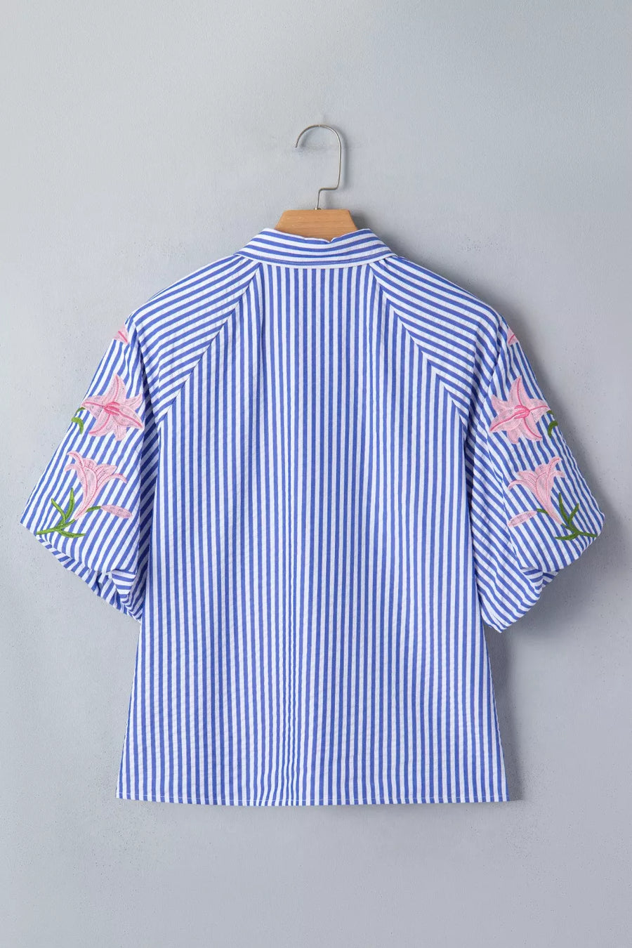 Blue and white striped button-down blouse with pink floral embroidery on the sleeves.