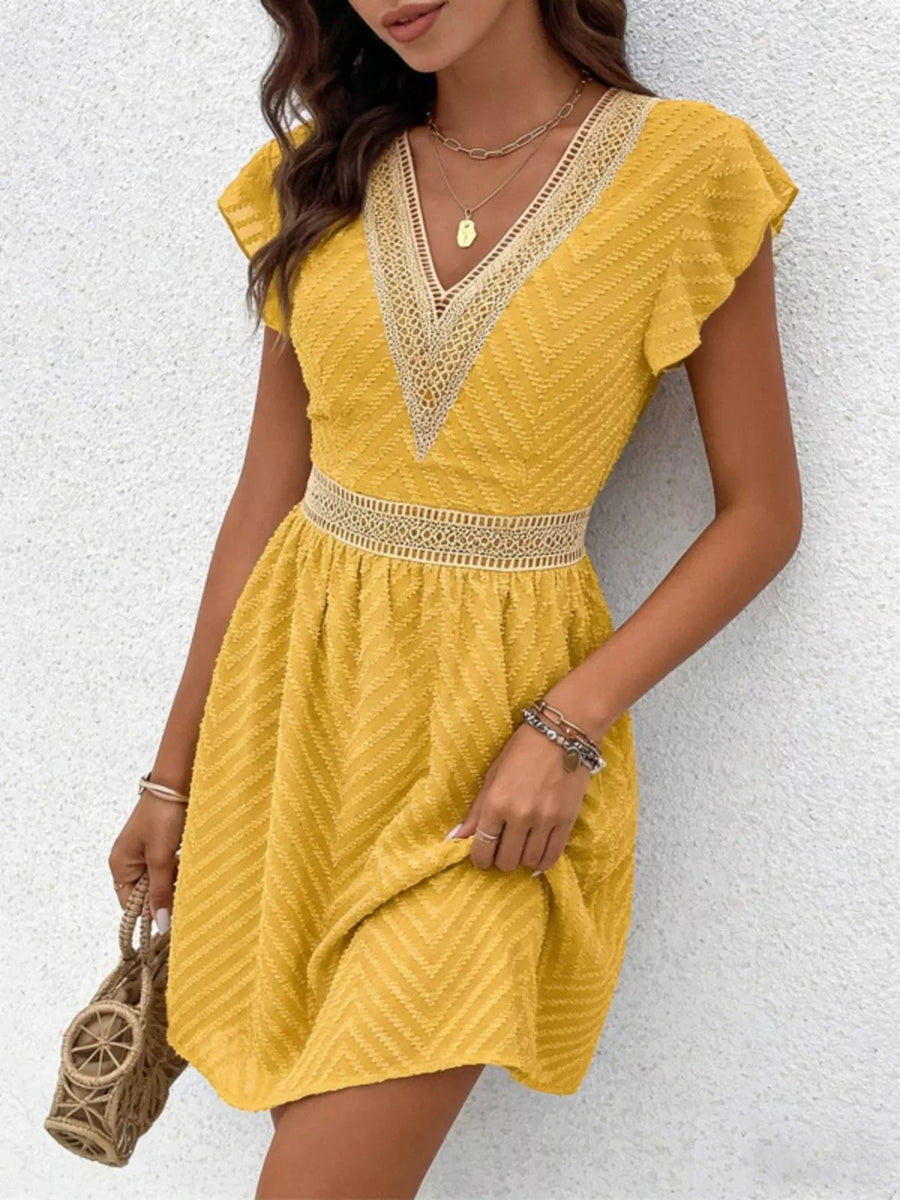 Chevron textured mini dress in gold with V-neck and defined waist, featuring lace trim.