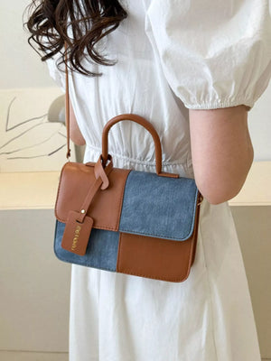 Chic two-tone PU leather handbag with brown and denim panels and top handle.