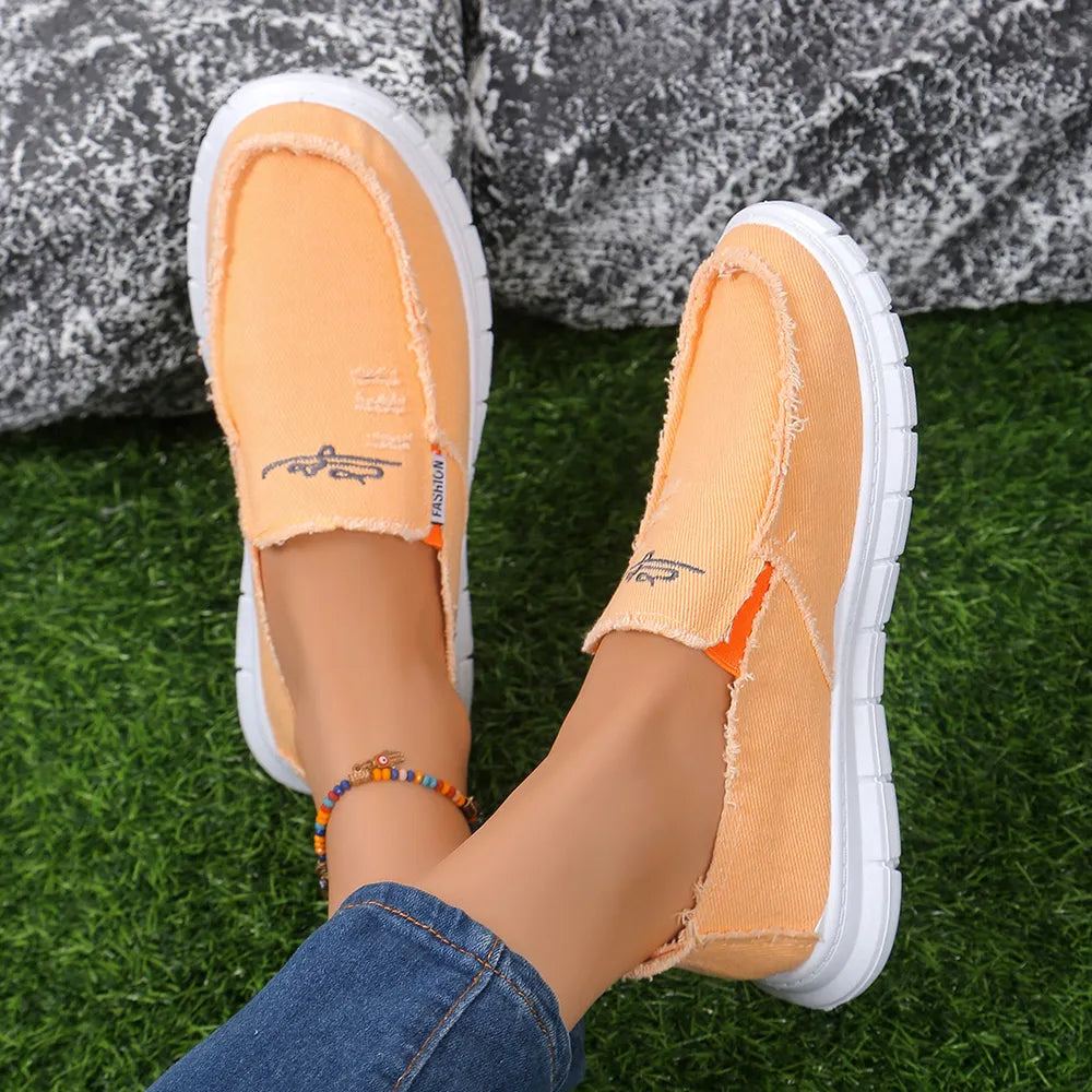 Orange canvas slip-on shoes with raw edges and embroidered detail.