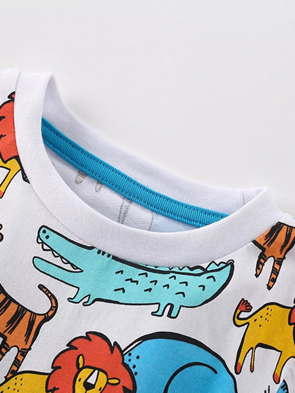 White cotton blend baby tee with colorful cartoon animal print and blue trim neckline.