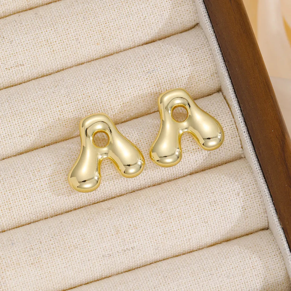 Gold sculptural stud earrings in the shape of the letter A.