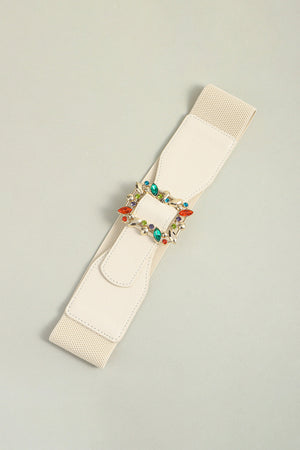 Ivory elasticated belt with a gold buckle adorned with colorful rhinestones.
