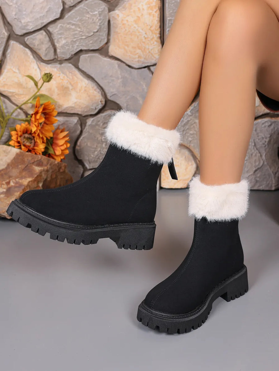 Black suede ankle boots with white faux fur trim and lug sole.
