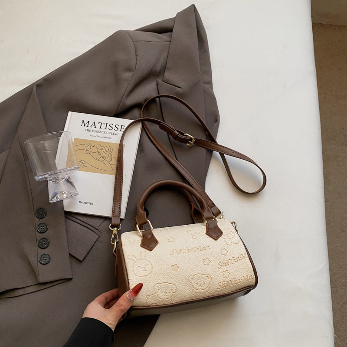 Mini crossbody bag in beige with cartoon bear and bunny pattern and brown trim.